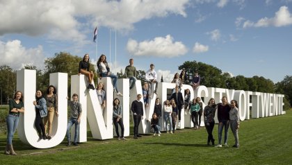 Logo UT buiten de campus met personen