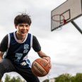 A boy playing basketball outside on our campus