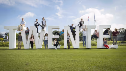 People standing around the letters T W E N T E