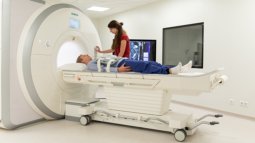 Student operates an MRI scanner while a patient lies on the table, ready for a scan.