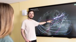 Two Cyber Security students engage with a large interactive screen showing a digital map with interconnected lines and nodes.