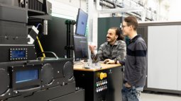 Interaction with industrial equipment and digital interface, highlighting integration of design processes and advanced manufacturing systems.