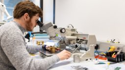 Electrical Engineering student works with a microscope and electronic components on a  lab workbench.
